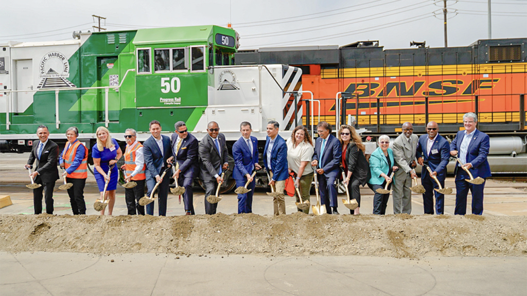 Federal, state, city and Port of Long Beach officials on July 18 celebrated the groundbreaking for the $1.57 billion Pier B On-Dock Rail Support Facility project. Pictured from left are Dr. Noel Hacegaba, Port of Long Beach Chief Operating Officer; Long Beach Harbor Commissioner Sharon L. Weissman; Long Beach Councilmember Kristina Duggan, 3rd District; Long Beach Councilmember Roberto Uranga, 7th District; Mark Tollefson, Undersecretary, California State Transportation Agency; Long Beach Harbor Commission President Bobby Olvera Jr.; Long Beach Mayor Rex Richardson; U.S. Transportation Secretary Pete Buttigieg; U.S. Rep. Dr. Robert Garcia, California 42nd District; Long Beach Councilmember Megan Kerr, 5th District; Port of Long Beach CEO Mario Cordero; Patricia Aguirre, Board Secretary, International Longshore and Warehouse Union Local 63; Long Beach Harbor Commission Vice President Bonnie Lowenthal; Long Beach Harbor Commissioner Steven Neal; Long Beach Councilmember Al Austin, 8th District; and Los Angeles City Councilmember Tim McOsker, 15th District. (Caption and Photograph Courtesy of POLB)